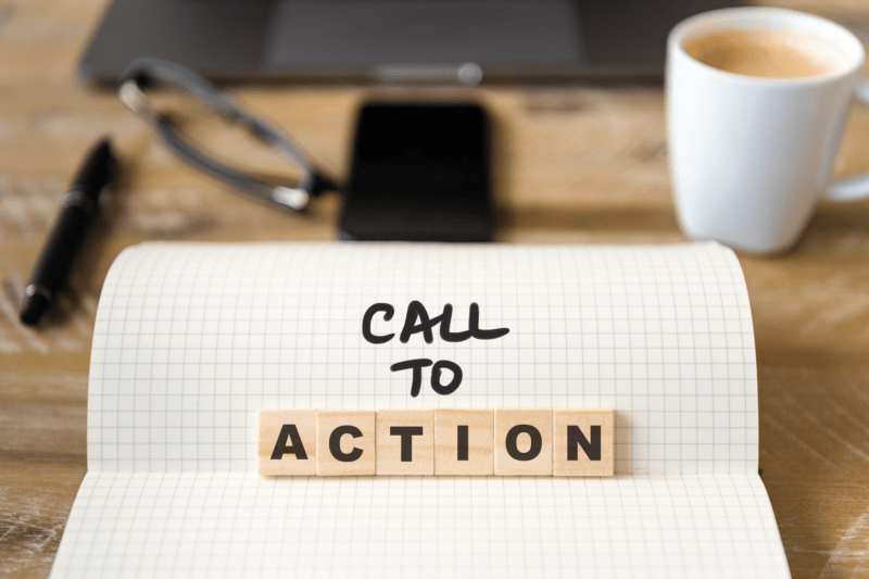 Image of white coffee mug in front of a Call to Action sign, spelled out with tiles